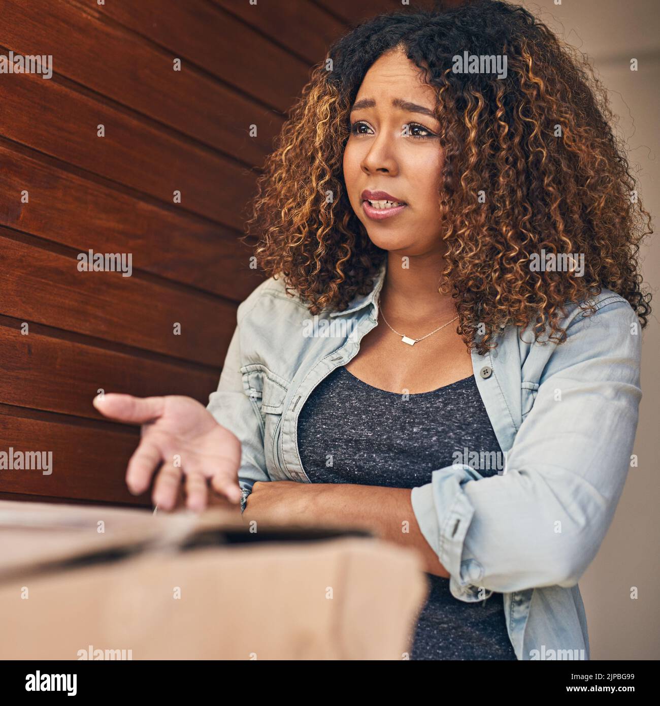 Das ist nicht das, was ich bestellt habe. Eine junge Frau, die aufgeregt aussieht, als sie eine Lieferung vom Kurier erhält. Stockfoto