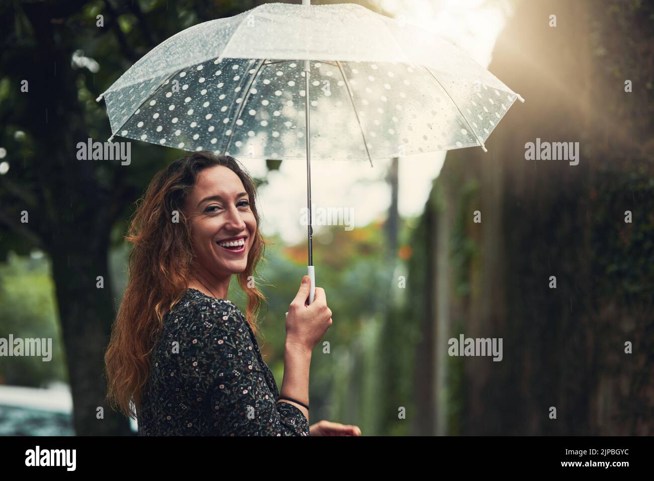 Wie ich den Regen verehre. Eine schöne junge Frau, die draußen im Regen läuft. Stockfoto