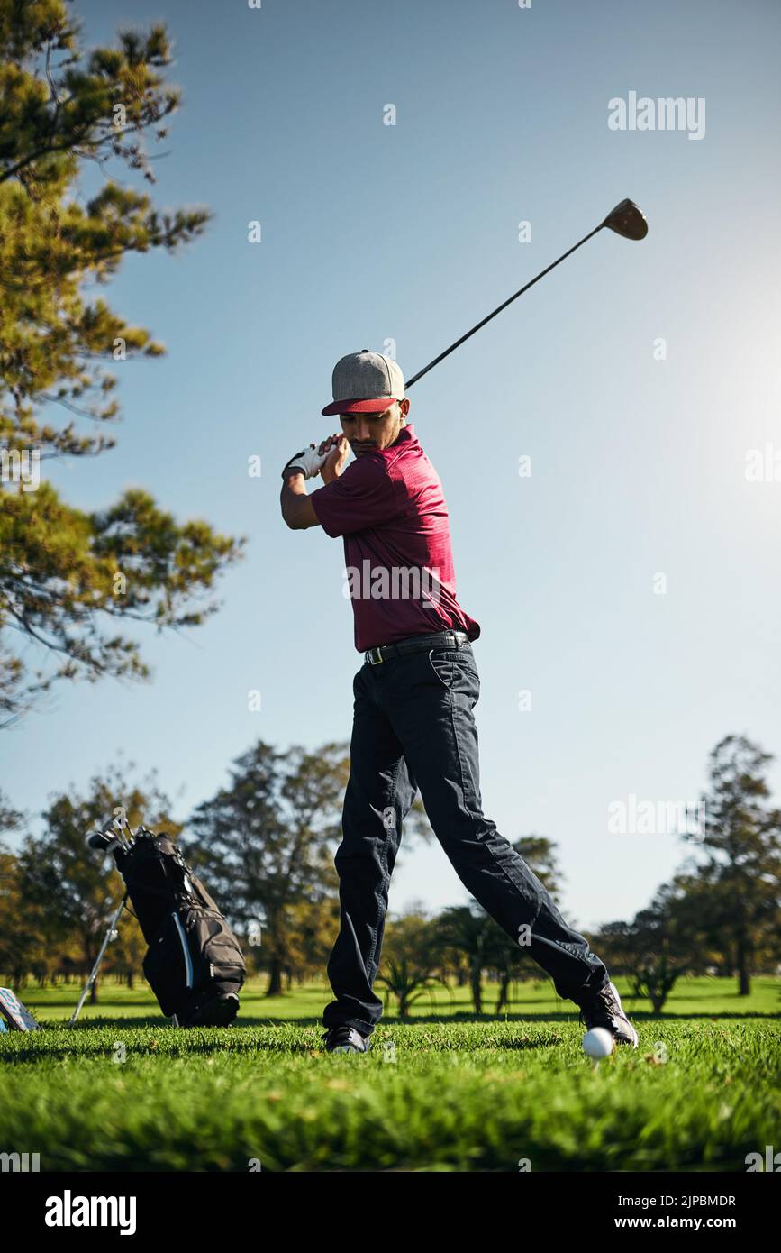 Du gehst aus hier Ball. Ein fokussierter junger Golfer im Begriff zu schwingen und spielen einen Schuss mit seinem Golfschläger draußen auf einem Kurs. Stockfoto