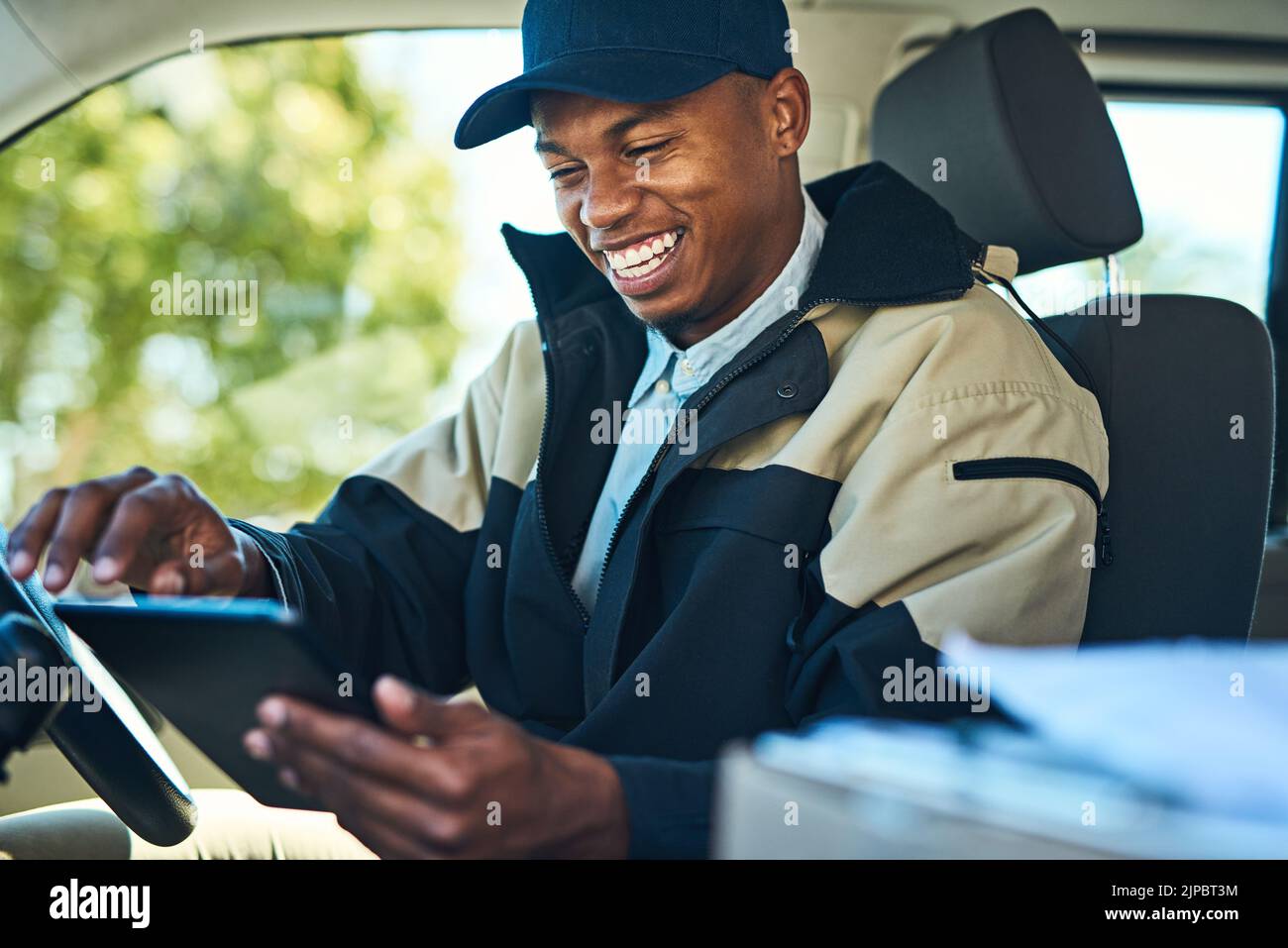 Seine Lieferungen sind alle digital organisiert: Ein Kurier mit einem digitalen Tablet, während er in einem Lieferwagen sitzt. Stockfoto