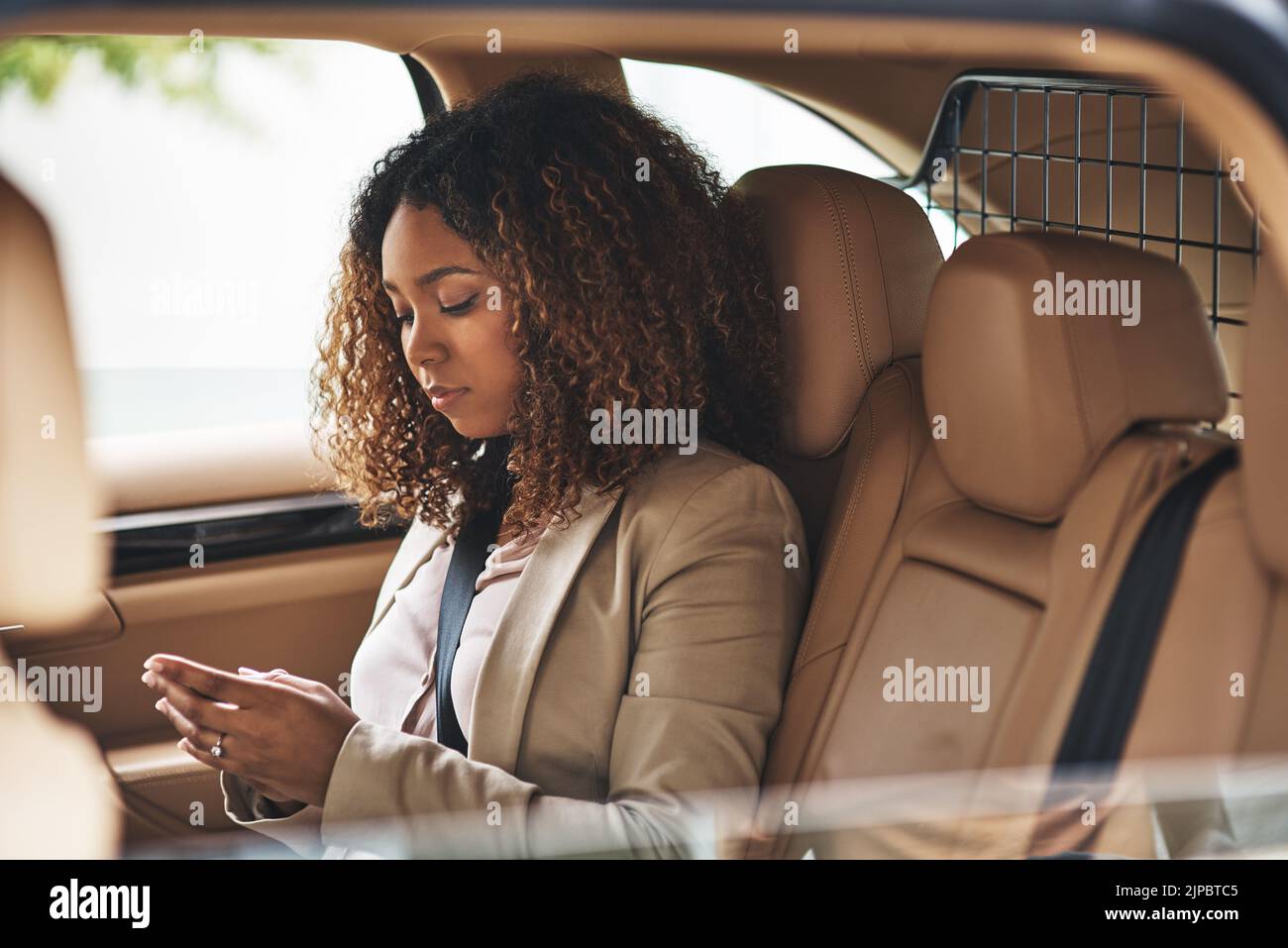 Meine Arbeit beginnt, bevor ich ins Büro komme. Eine attraktive Geschäftsfrau, die am Morgen ein Mobiltelefon benutzt. Stockfoto