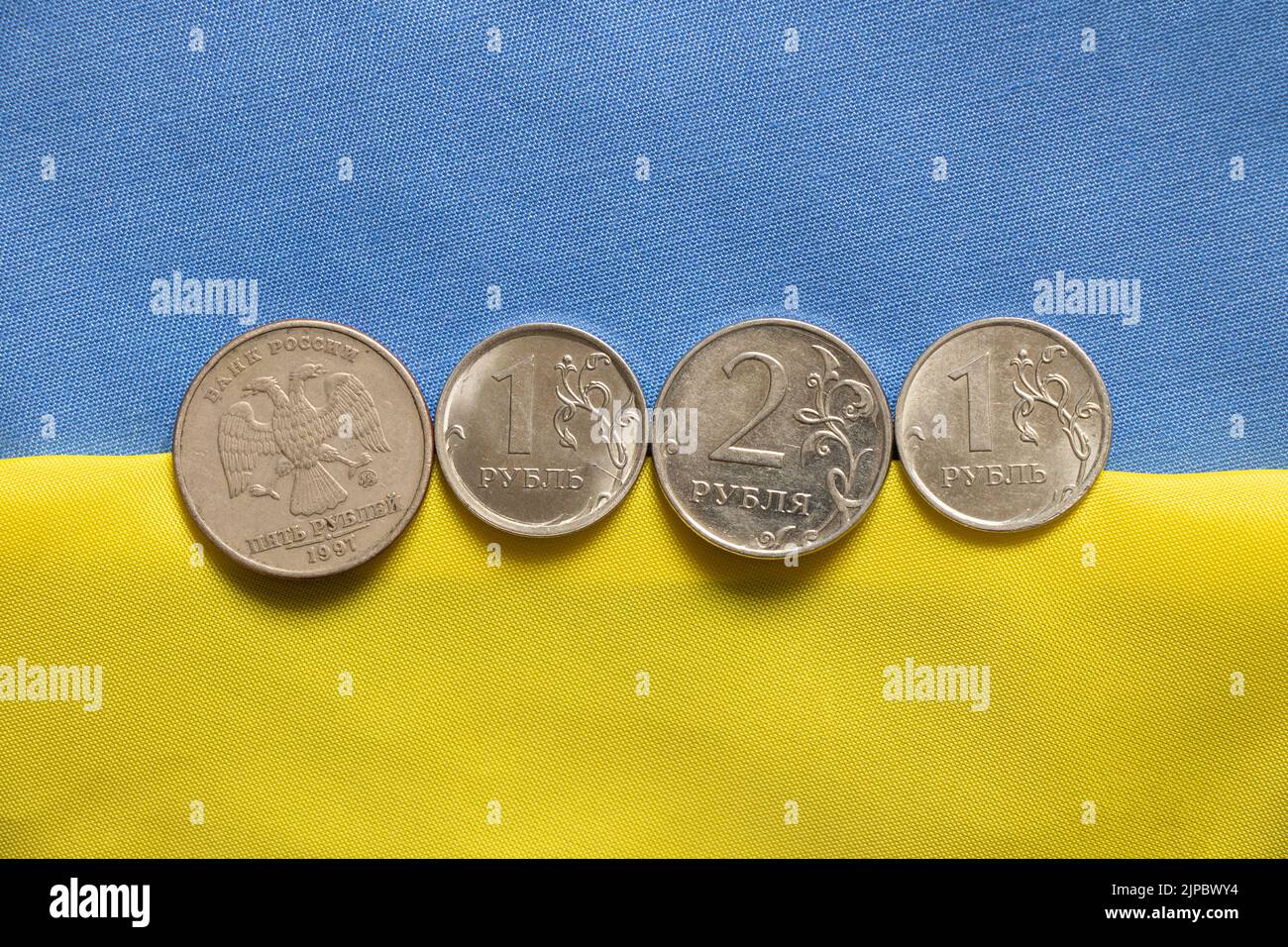 Der russische Rubel liegt auf der ukrainischen nationalen gelb-blauen Flagge, der Sturz des Rubels, Sanktionen gegen Russland, der finanzielle Zusammenbruch in Russland, Stockfoto