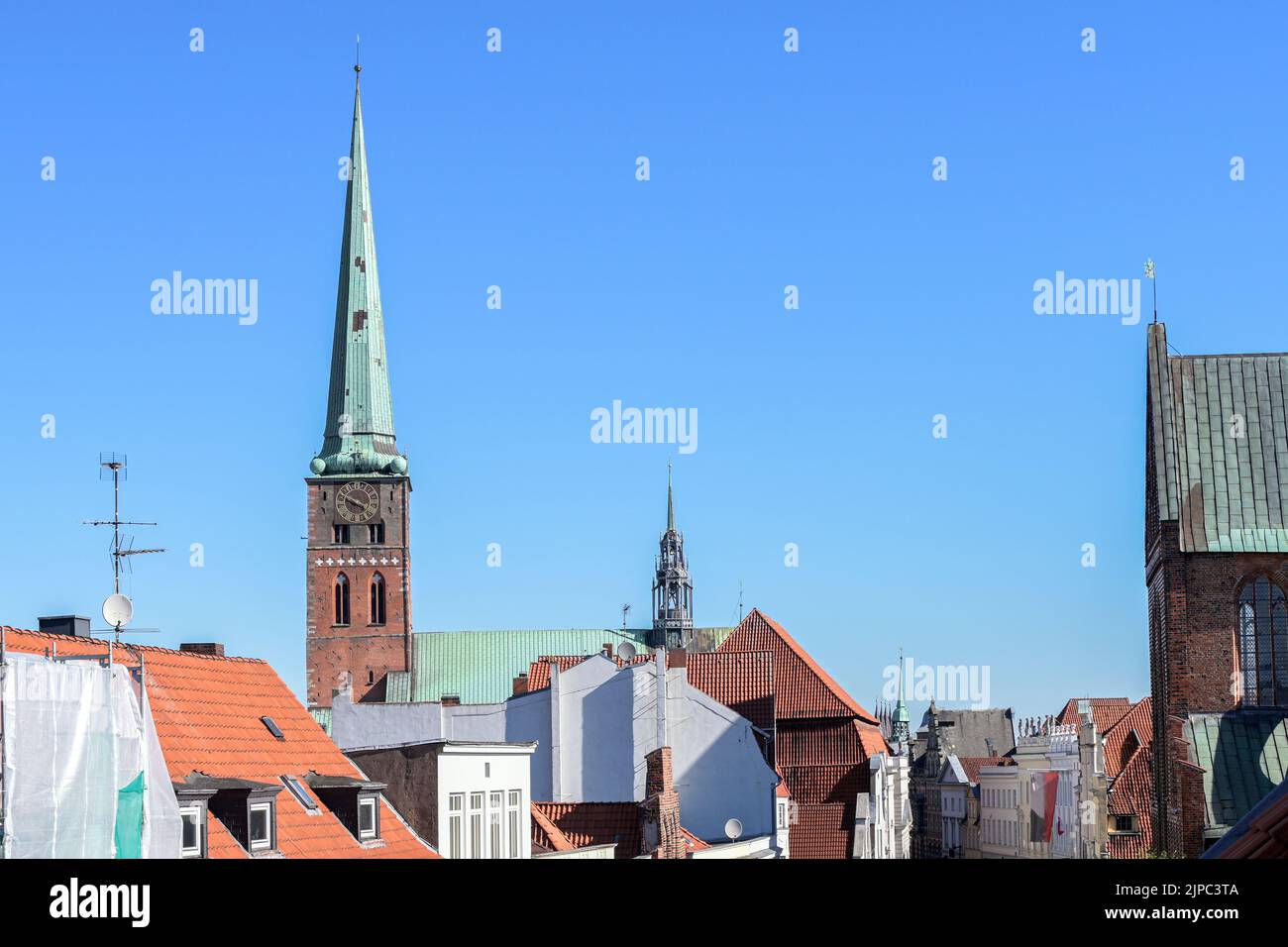 St. Jakobi Kirche mit Uhrturm und Firstturm hinter den Dächern der Lübecker Altstadt unter blauem Himmel, Kopierraum, ausgewählter Fokus Stockfoto