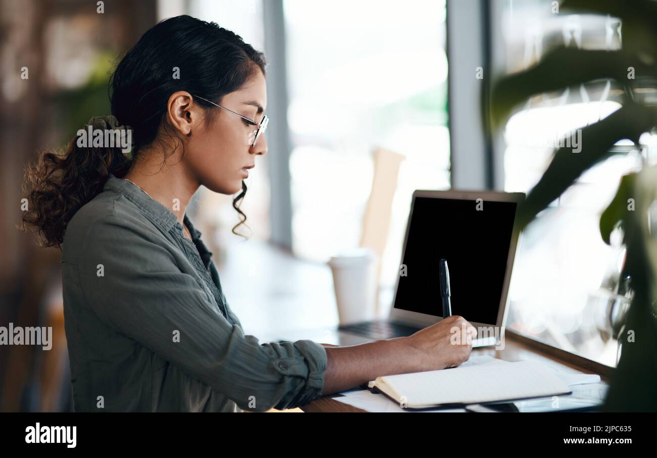 Schreiben, seriöse und freiberufliche junge Frau, die mit Laptop und Notebook in einem Café arbeitet. Kreative Planung von Telearbeitern oder Studentinnen Stockfoto