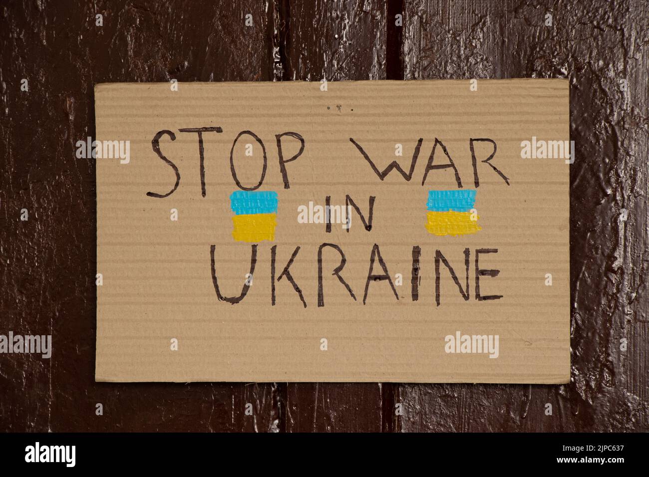 Papierschilder mit Slogans stoppen den Krieg in der Ukraine an der braunen Tür des Hauses, den Krieg in der Ukraine 2022 Stockfoto