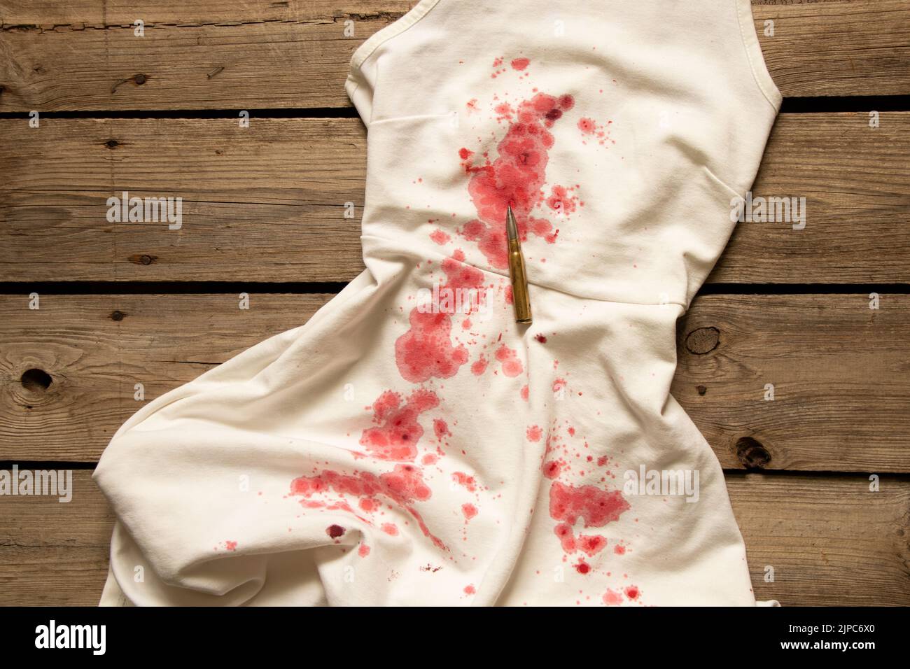 Weißes Frauenkleid mit Blutstropfen und einer Kugel, ein Tatort, Mord an einer Frau, Blut an Dingen Stockfoto