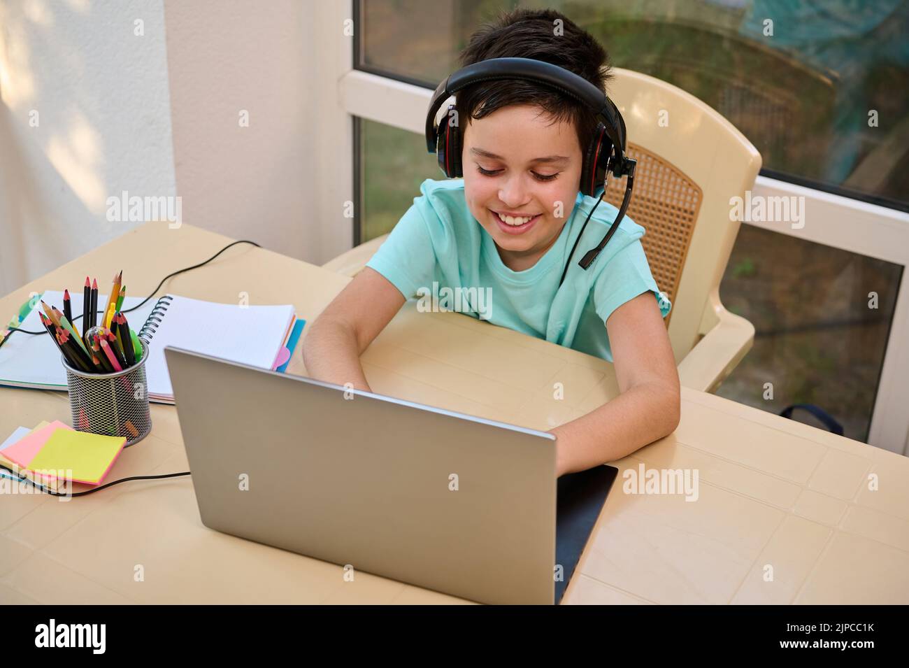 Schuljunge mit Kopfhörern. Fernunterricht online im virtuellen Kurs mit Lehrer Tutor auf Laptop per Videokonferenz Stockfoto