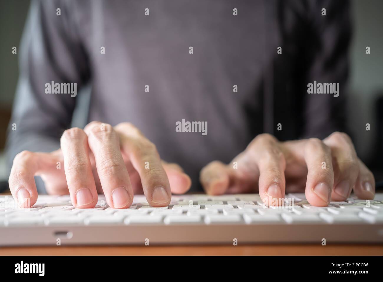 Ein Mann, der auf einer flachen Computertastatur tippt Stockfoto