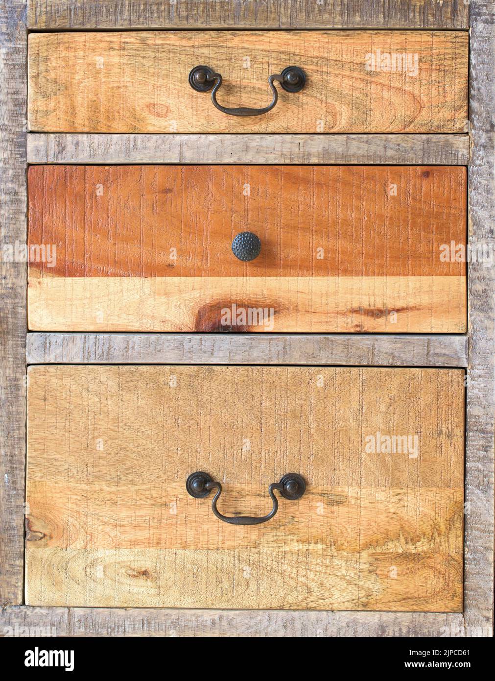 Eine antike hölzerne Kommode mit Metallgriffen, verschiedene alte Holzkisten Stockfoto