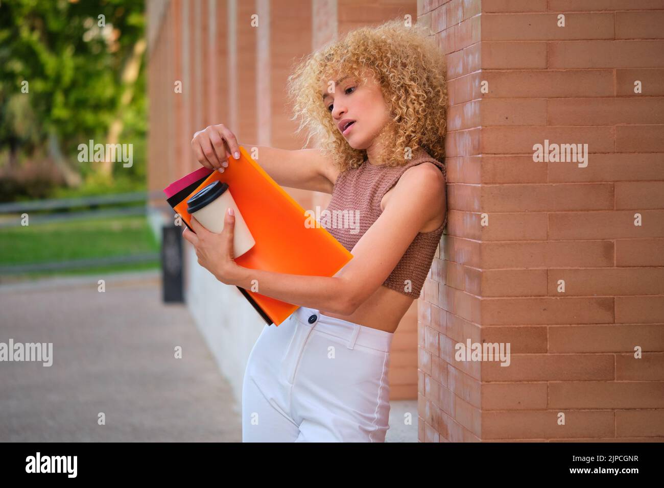 Junge brasilianische Universitätsstudentin, die bei einem Kaffee gegen die Wand studiert. Stockfoto