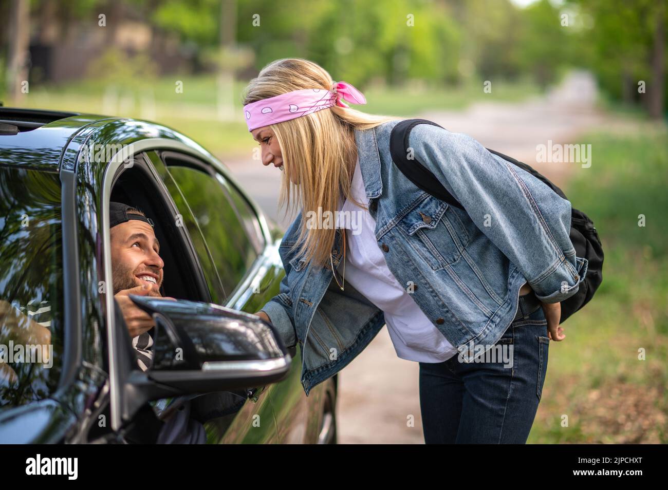 Blonde Frau zeigt einem Mann im Auto den Weg Stockfoto