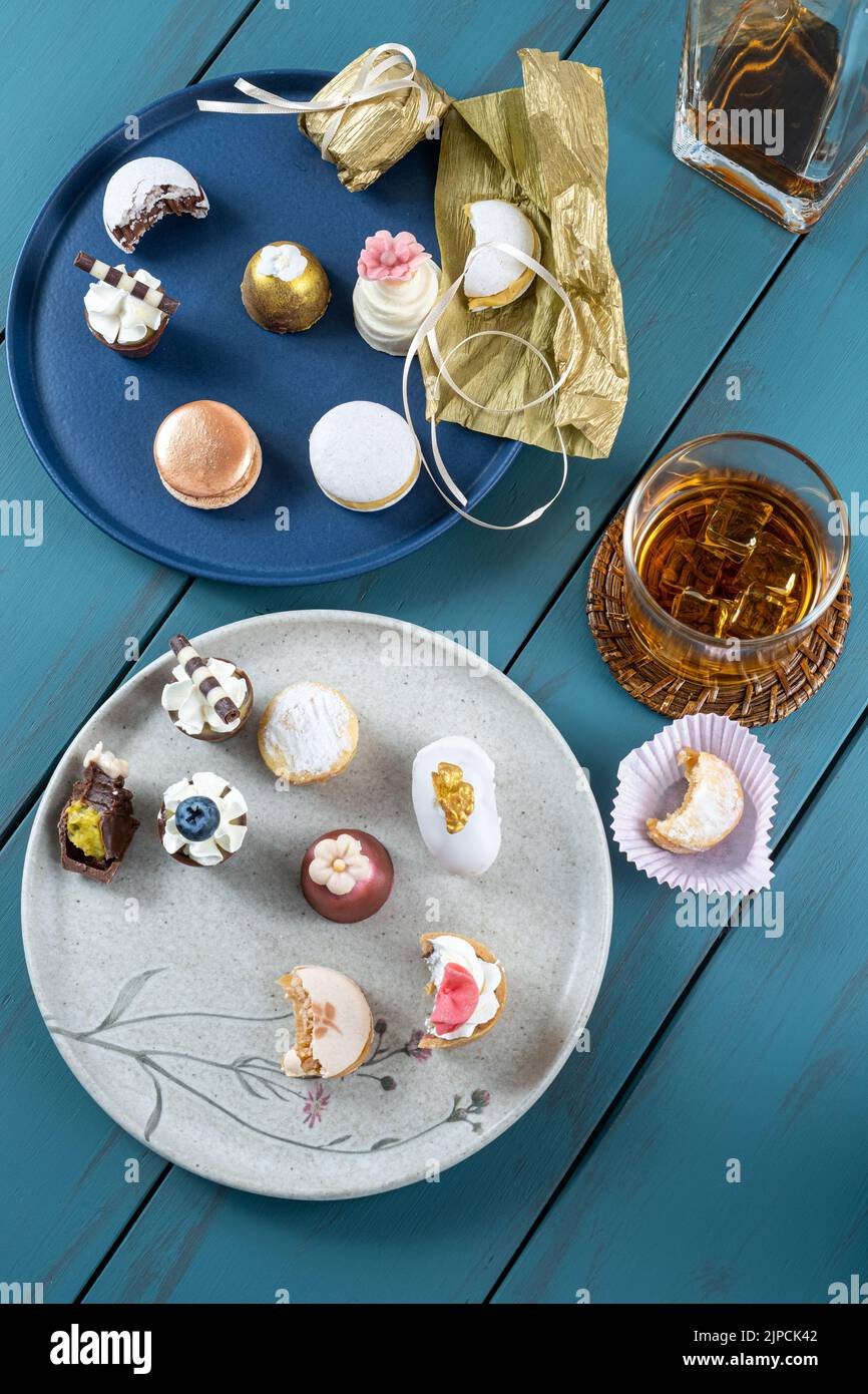 Macaron neben Trüffel, Hochzeitslieblichkeit, Walnusskameo, Flasche und Glas Whiskey. Stockfoto