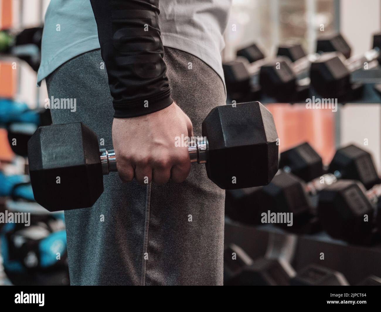 Kraftvoller Bodybuilder, der die Übungen mit Hanteln macht. Foto eines starken Mannes im Fitnessstudio. Stärke und Motivation. Stockfoto