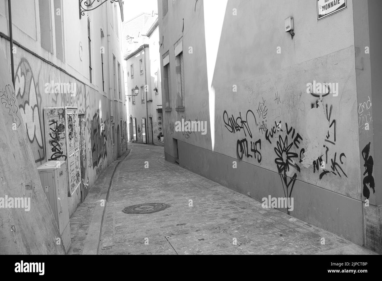 Die Graustufen der engen Straßen mit Graffiti-Kunst und Texten an den Fassadenwänden Stockfoto