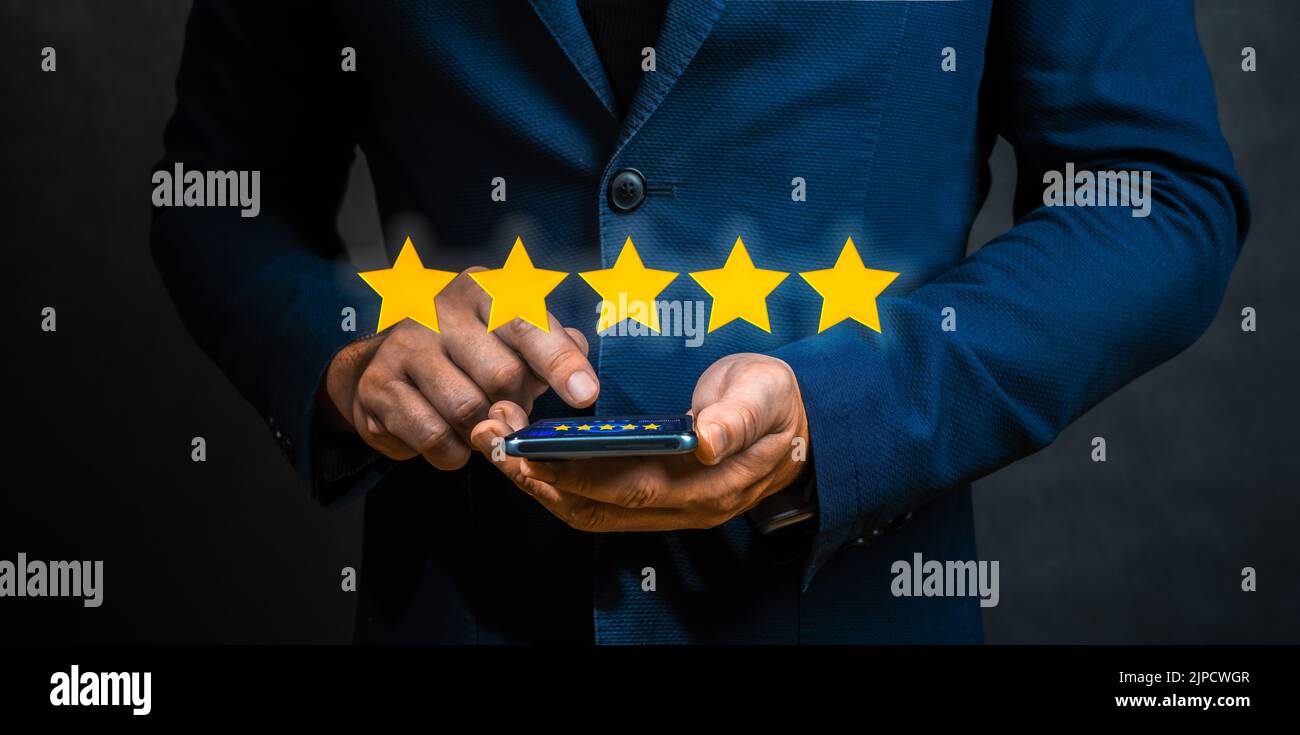 Geschäftsmann zeigt fünf-Sterne-Symbol, um die Bewertung des Unternehmens zu erhöhen. Mann Bewertet Mobile Anwendung Auf Smartphone Mit Fünf Sternen. Kundenbewertung Stockfoto