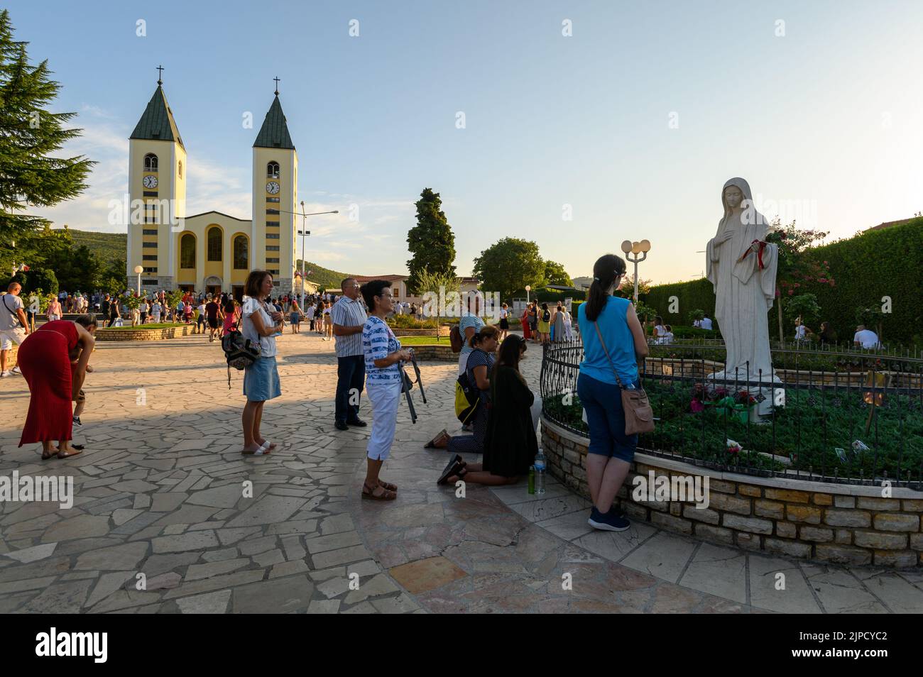 Die Menschen beten vor der Statue der Jungfrau Maria, der Königin des Friedens, vor der Kirche des hl. Jakobus in Medjugorje, Bosnien und Herzegowina. Stockfoto