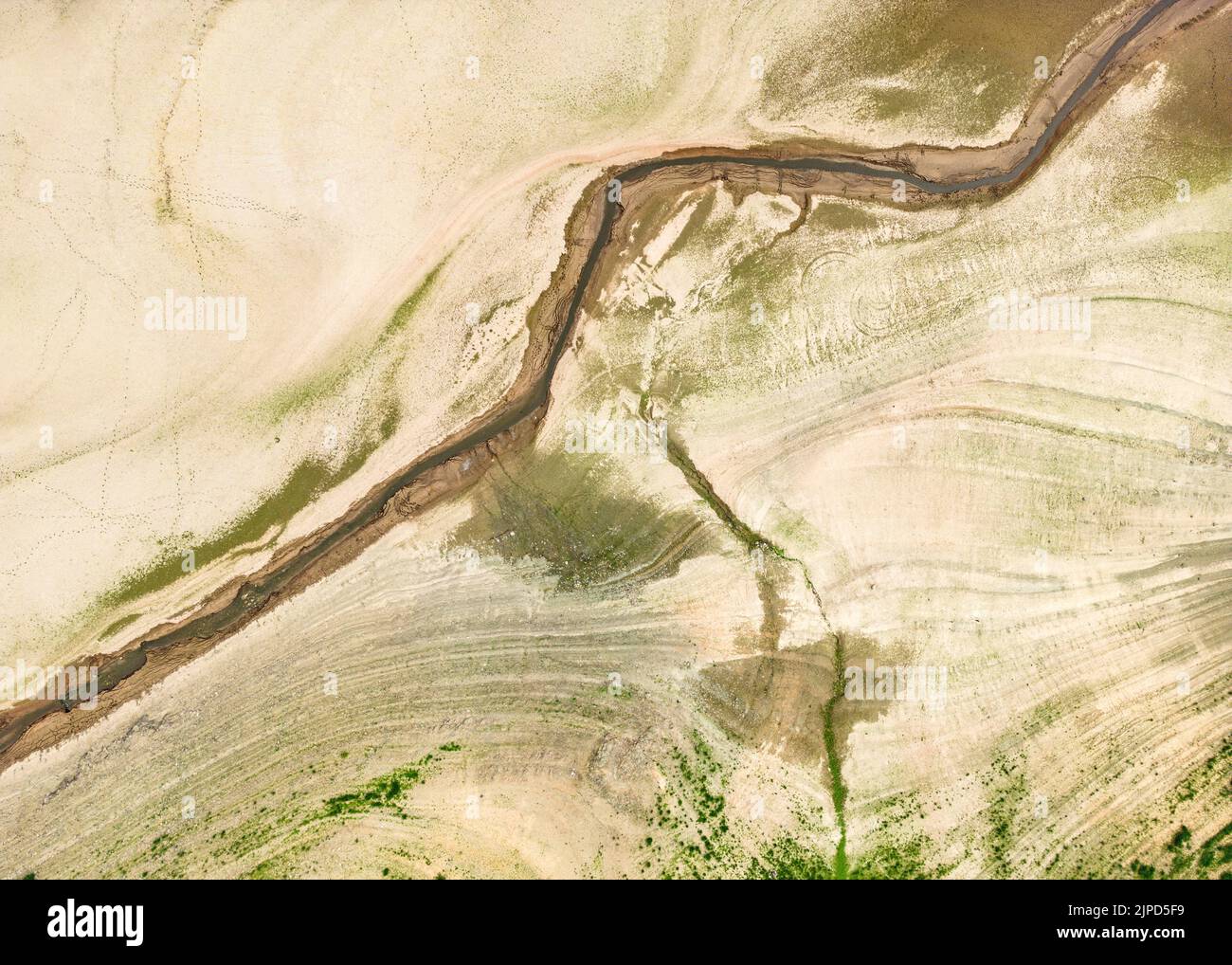 Scheid, Deutschland. 17. August 2022. Nicht mehr als ein Rinnsal ist der kleine Fluss 'Werbe', der durch den fast trockenen Edersee bei Scheid fließt (Luftaufnahme mit Drohne). Auf dem weitgehend leeren Edersee in Nordhessen sind die Boote fast trocken. Der Wasserstand des Stausees wurde massiv gesenkt, um die Navigation auf der Oberweser zu sichern, zusätzlich zu wochenlanger Dürre. Quelle: Boris Roessler/dpa/Alamy Live News Stockfoto