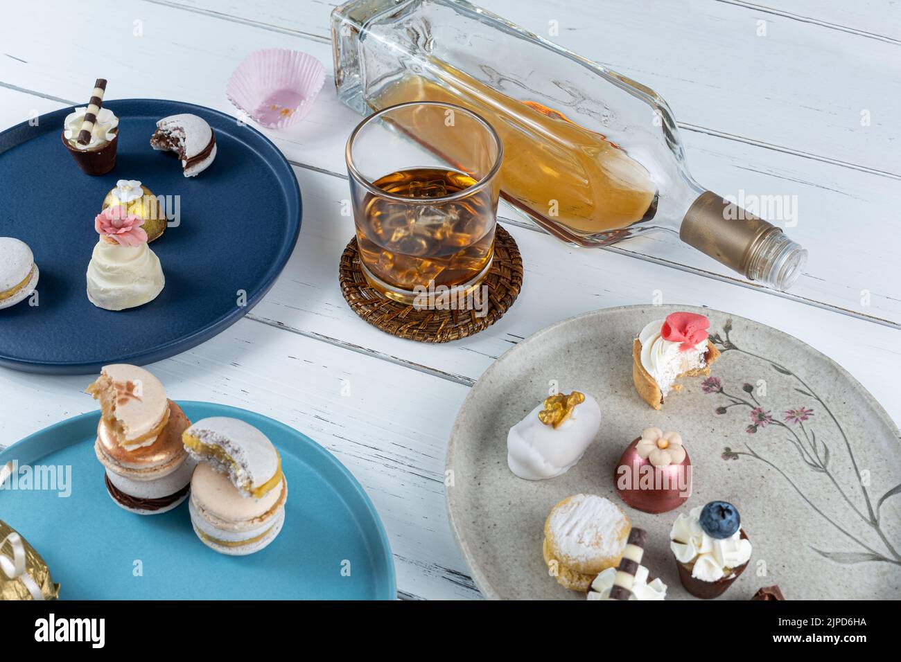 Glas mit Whiskey und Eis, umgeben von raffinierten Hochzeitsbonbons. Stockfoto