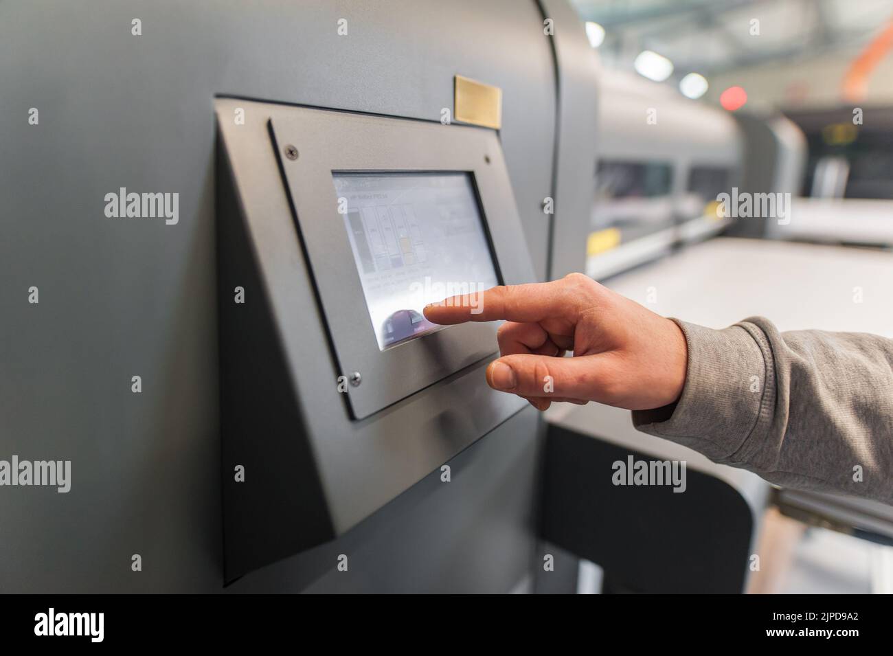Techniker, der den ein- und Ausgabestatus auf der Touchscreen-Monitorstation auf der Vorderseite des Digitaldruckereibüros überprüft Stockfoto