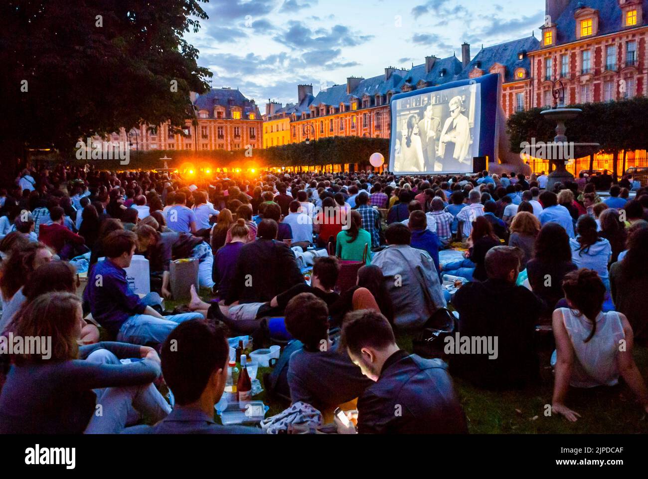 Paris, Frankreich, große Menschenmengen, die auf dem Rasen sitzen, von hinten, Publikum von hinten bei der Open Air Cinema Show im Stadtpark, dem „Place des Vosges“ Town Square Stockfoto