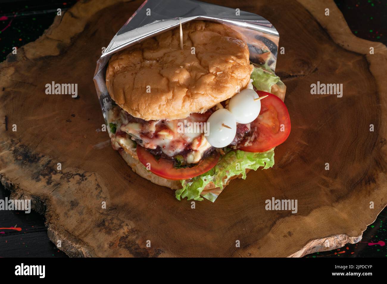 Nahaufnahme eines kolumbianischen Hamburgers in einem Fast-Food-Stand auf der Straße. Brot, Salat, Tomaten, Hamburger-Fleisch, Mozzarella-Käse, Speck Stockfoto