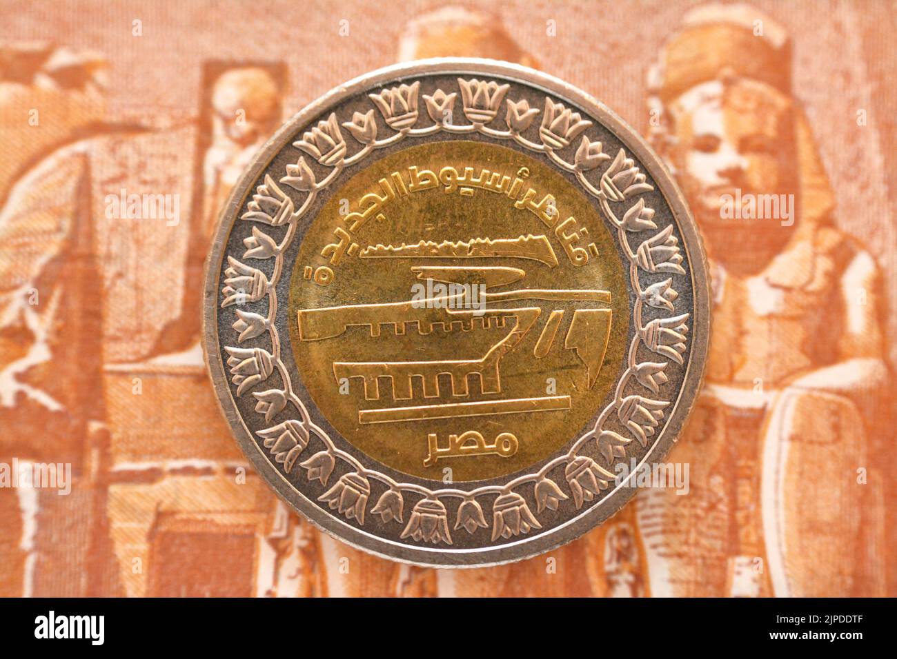 Neuer Slogan des Asyut-Stadtsperrprojekts von der Vorderseite der 1 LE EGP-Münze ein ägyptisches Pfund Geld auf einem verschwommenen Hintergrund der Rückseite eines p Stockfoto