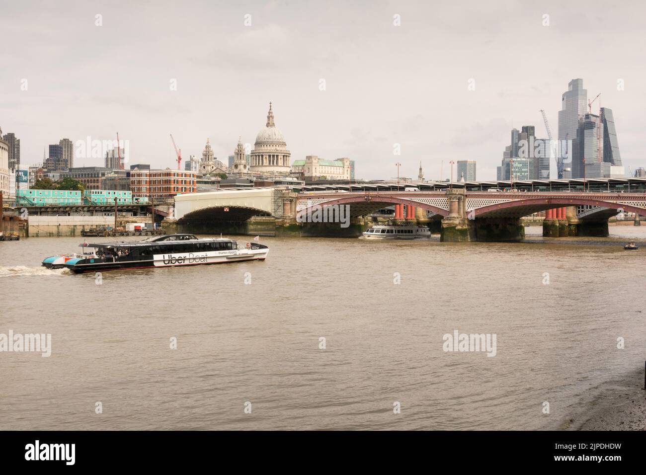 Ein Uber-Boot nähert sich der neuen Eisenbahnbrücke Blackfriars Station mit der St Paul's Cathedral und der Skyline der City of London im Hintergrund Stockfoto
