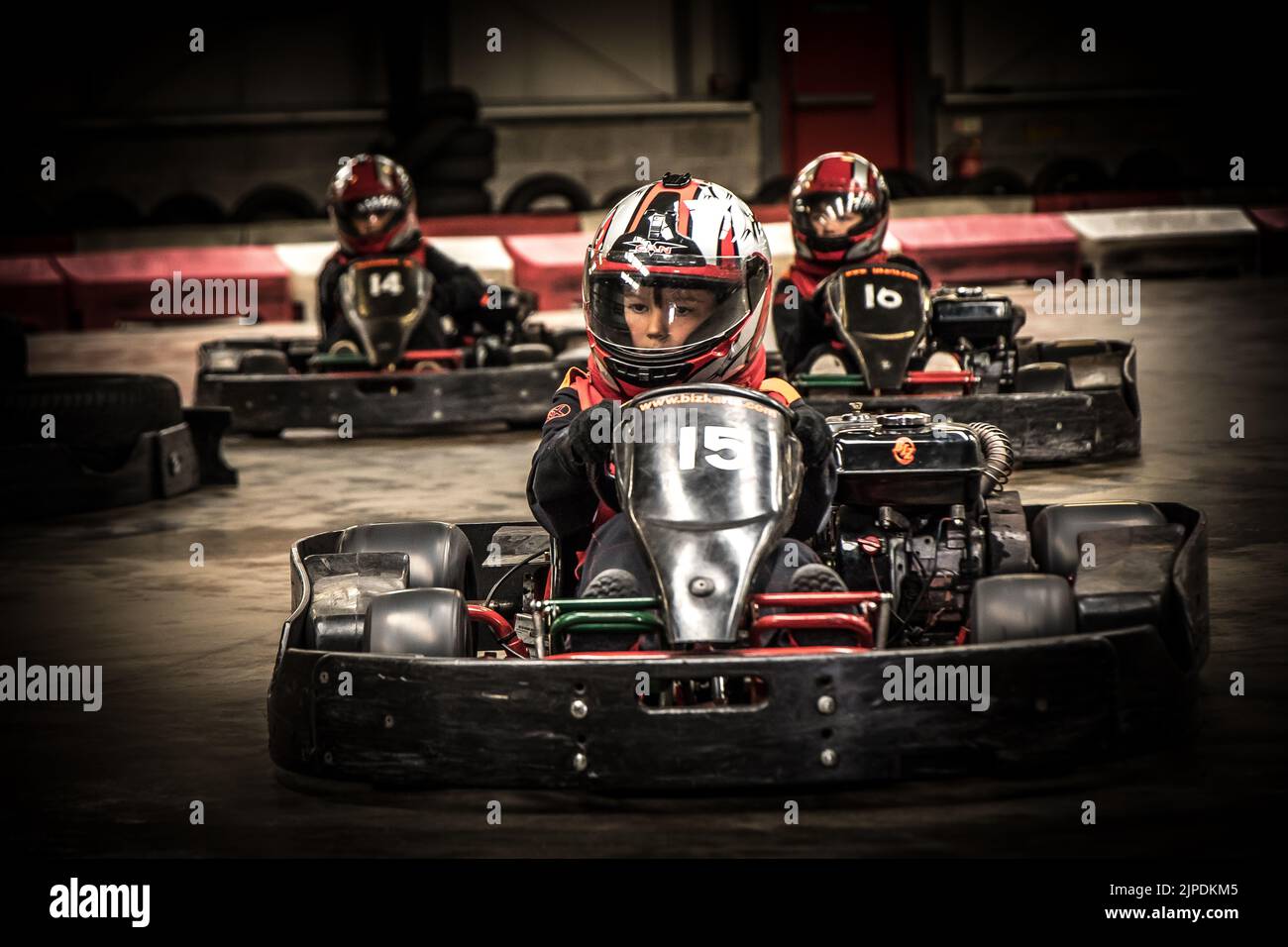 3 Jungen mit Sturzhelmen Rennen sich in Go Karts Stockfoto
