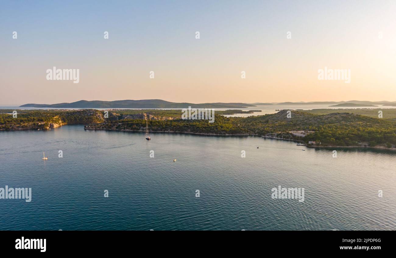 Luftdrohnenaufnahme des Sonnenuntergangs über den Kornati Inseln in der Nähe der Stadt Sibenik, Kroatien. Wasserbucht mit Booten und sanftem Sonnenlicht. Stockfoto