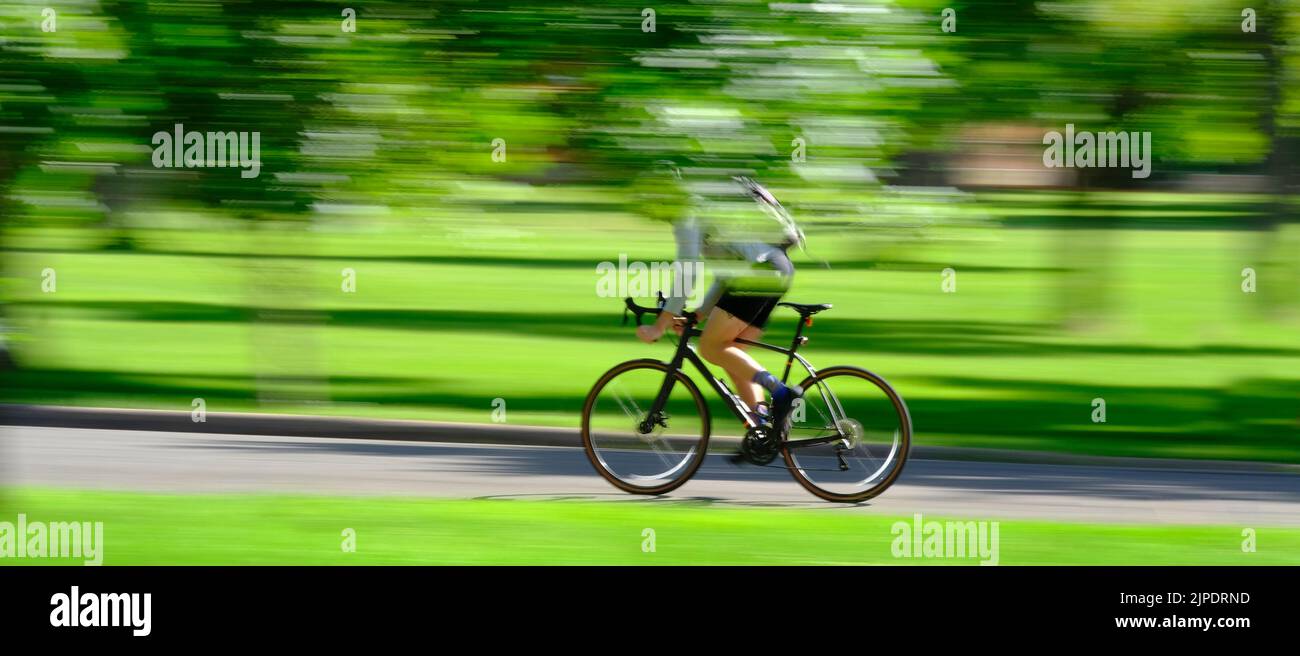 Person, die im Sommer Fahrrad oder Fahrrad im grünen Park fährt, bewegt sich schnell verschwommene Geschwindigkeit verschwommene Bewegung Stockfoto