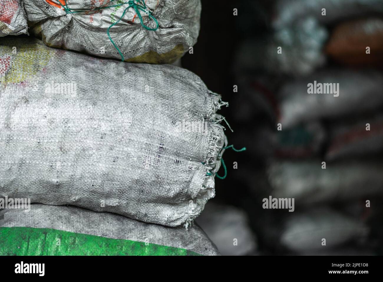 Detaillierte Ansicht von weißen Säcken mit Material und Produkten in einem dunklen Lager gefüllt. Säcke mit Kohle gefüllt bereit verarbeitet und verkauft werden Stockfoto