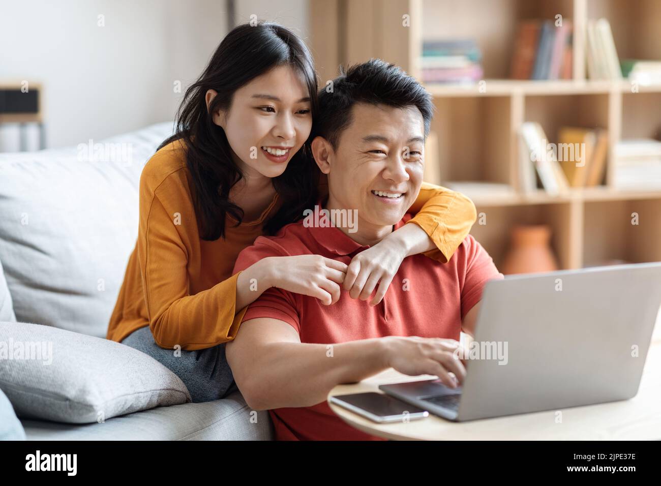 Glückliche japanische Liebhaber planen Urlaub, mit Computer Stockfoto