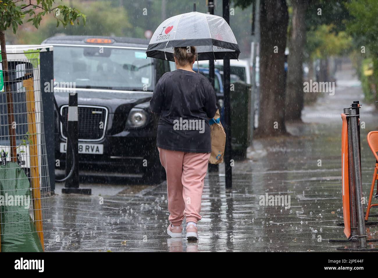 London, Großbritannien. 16. August 2022. Eine Frau schützt sich bei nassem Wetter in London unter einem „I Love London“-Regenschirm vor Regen. Das Met Office hat in den nächsten Tagen eine gelbe Wetterwarnung für Gewitter und schwere Regenfälle in den meisten Teilen des Landes herausgegeben. (Foto von Dinendra Haria /SOPA Images/Sipa USA) Quelle: SIPA USA/Alamy Live News Stockfoto