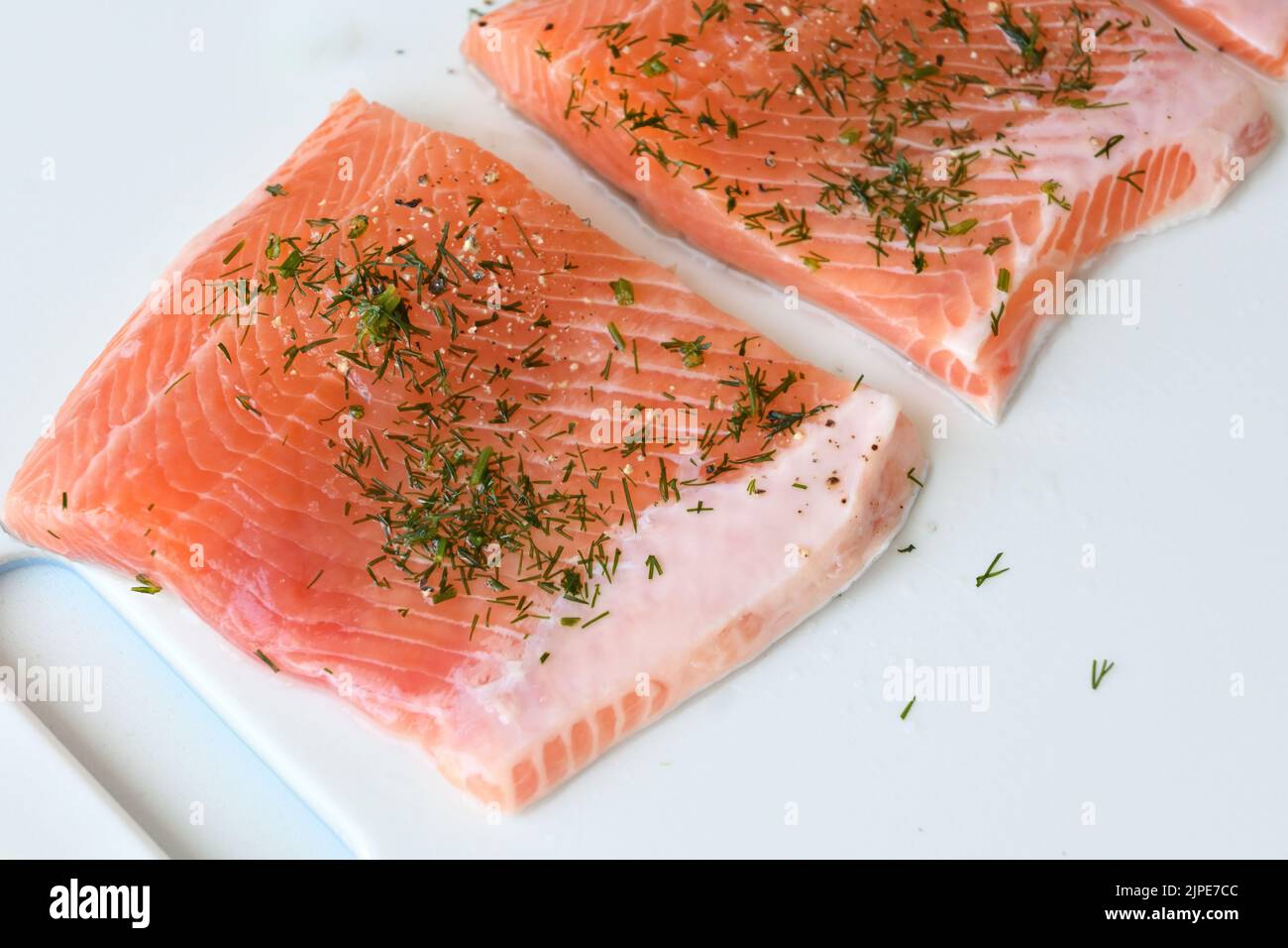 Stücke von roher Forelle mit Gewürzen bestreut Stockfoto