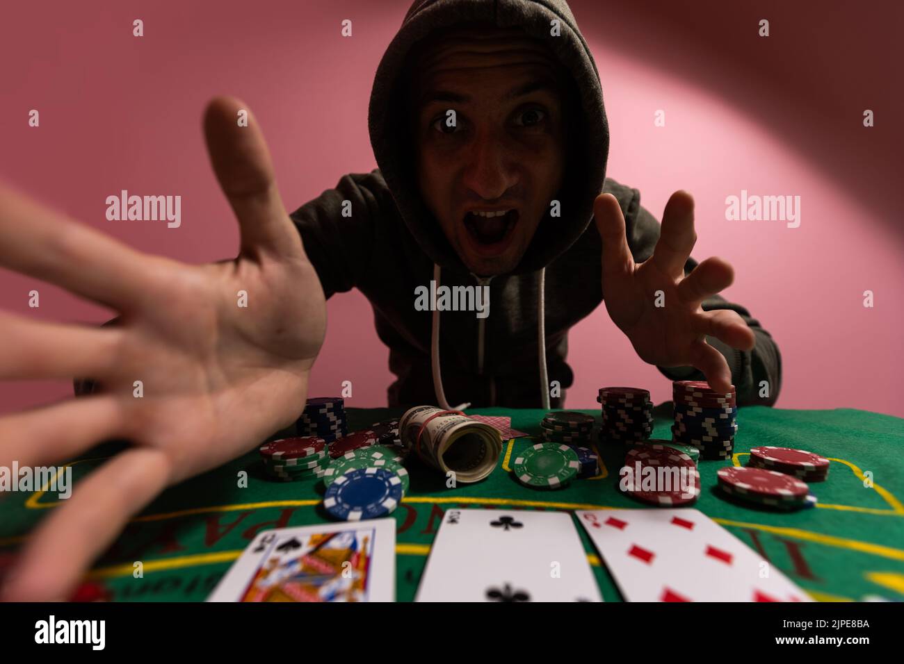 Unglücklicher junger Mann, der sich traurig, verzweifelt und gestresst fühlt, nachdem er sein Geld beim Poker und Blackjack in einem nächtlichen Casino verloren hat Stockfoto