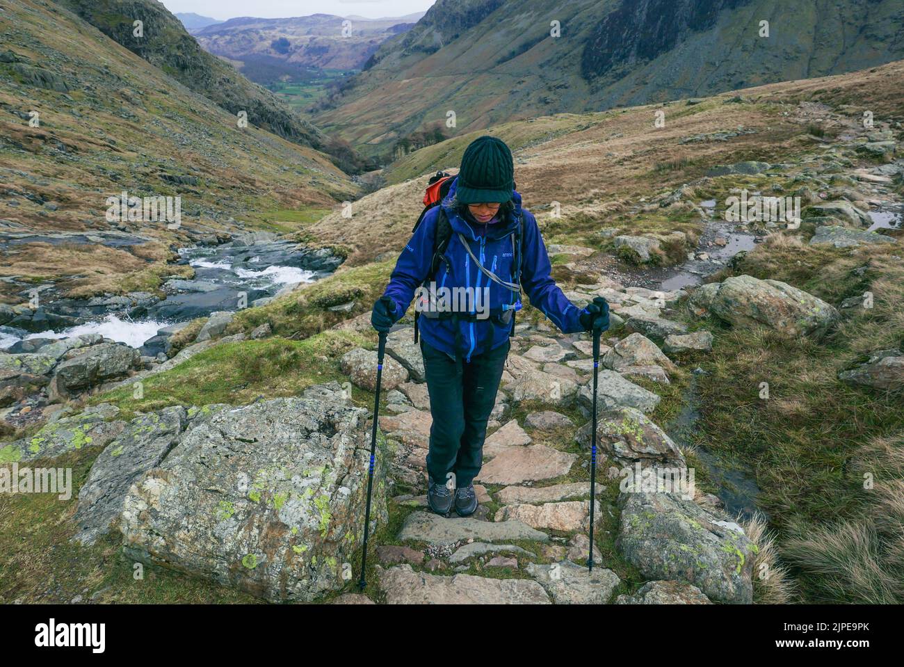 Weibliche Wandererin, die einen Bergpfad in Richtung Styhead Tarn in Borrowdale, Lake District National Park, Cumbria, hinaufgeht Stockfoto