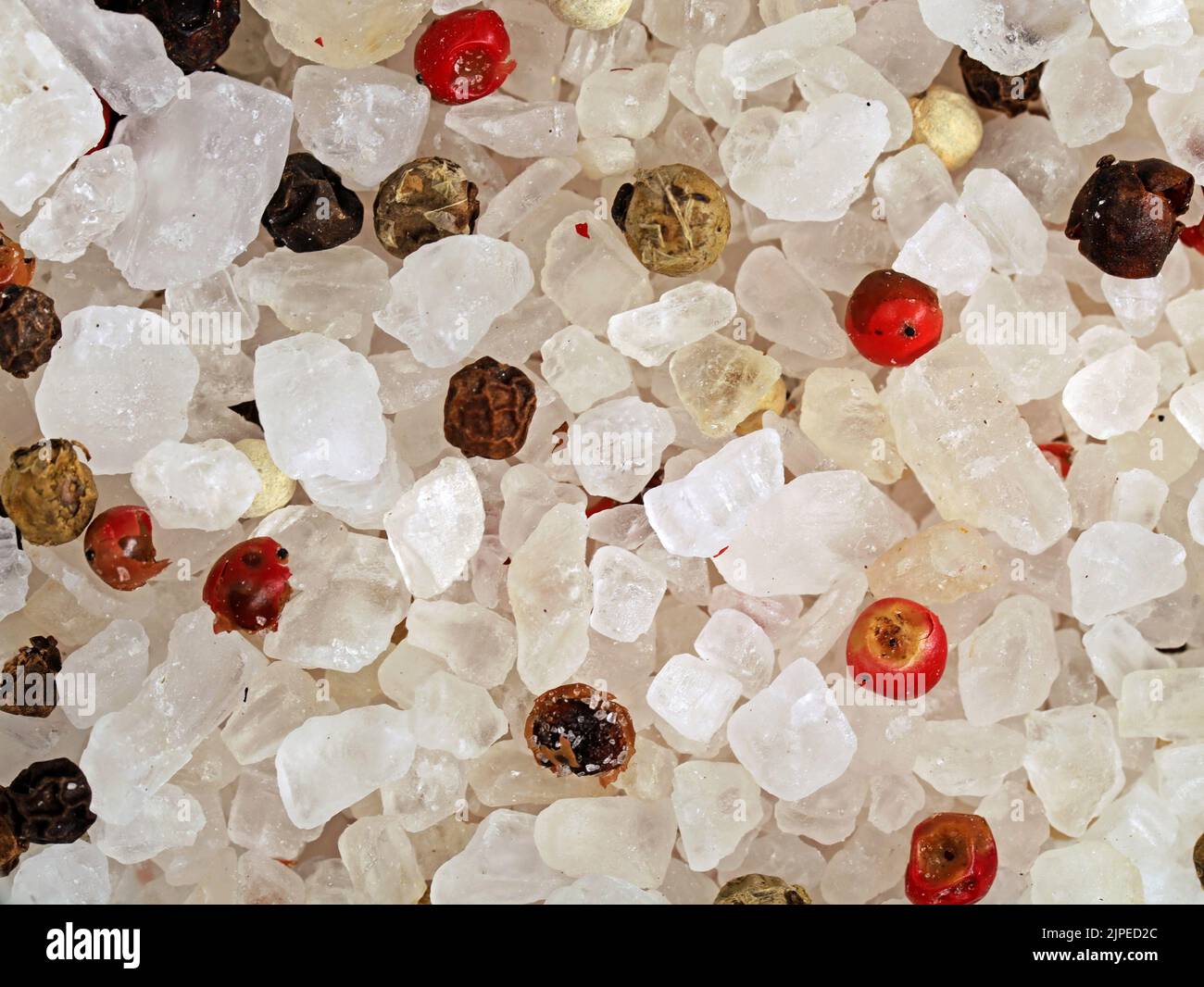 Nahaufnahme von grobem Salz und gemischten farbigen Pfefferkörnern, Gewürzstruktur Hintergrund Stockfoto