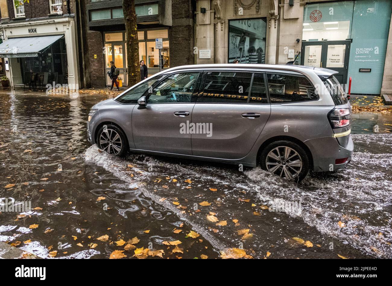 Das Auto fährt durch die überflutete Store Street im Zentrum Londons nach terrentiellem Regenguss, England, Großbritannien, Klimawandel. Stockfoto