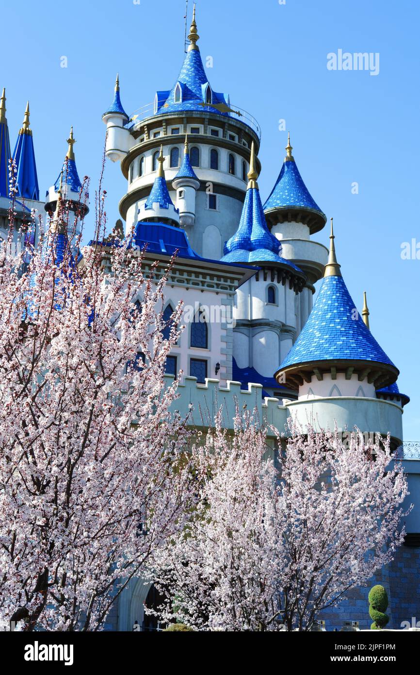 Blue Vintage Castle hinter blühenden Bäumen mit klarem Himmel im Hintergrund Stockfoto