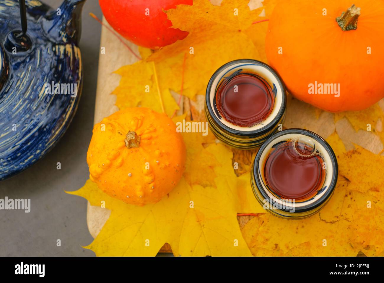Herbsttee.Tassen mit heißem Getränk und Kürbissen mit Ahornblättern. Teeparty im Herbstgarten. Herbst gemütliche Stimmung Stockfoto