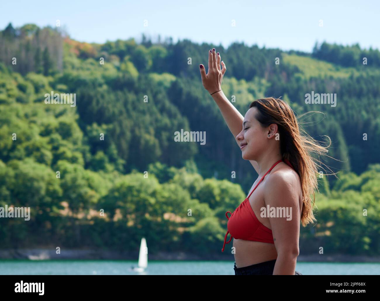 Eine schöne junge Dame, die mit ihrer Hand in Lac de la Haute-sure, Luxemburg, lächelt Stockfoto