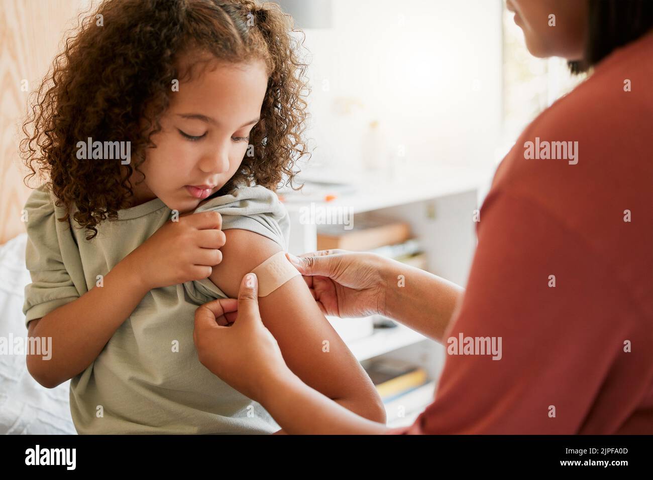 Covid Krankenschwester, die ein Kind impft, indem sie in einer Klinik einen Verband anlegt. Arzt, der das Mädchen nach einer Injektion im Gesundheitszentrum mit Gips bespritzt. Pädiatrie Stockfoto
