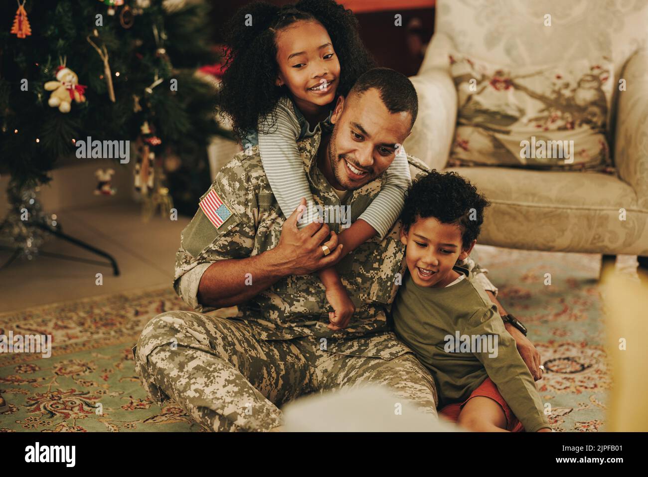 Fröhliche Militärfamilie, die fröhlich lächelt, während sie Weihnachten zusammen verbringt. Glücklicher Militärvater, der sich zu Weihnachten mit seinen Kindern wiedervereinigt. Soldat spen Stockfoto