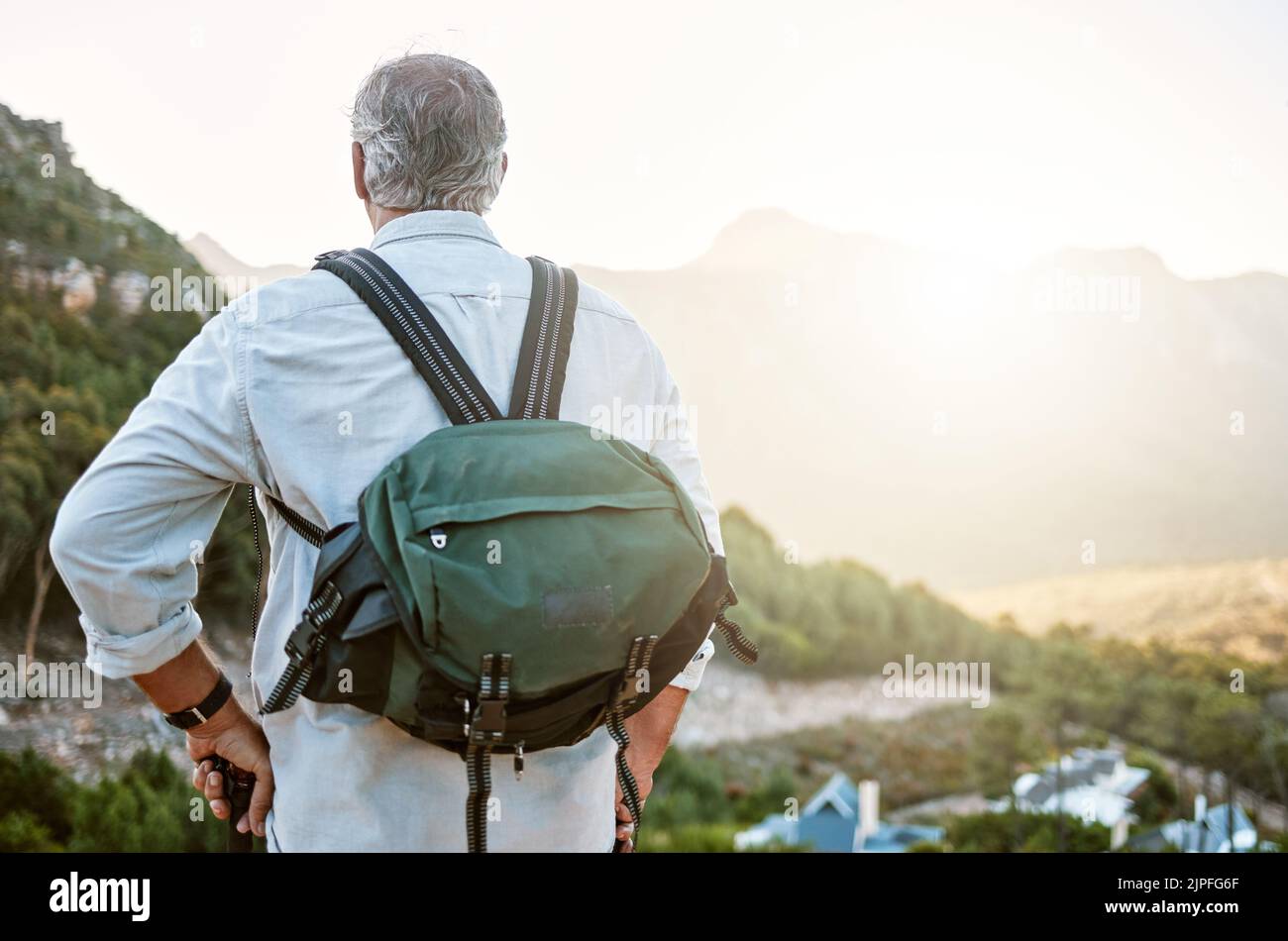 . Rückansicht des aktiven und abenteuerlichen Senior-Mannes, der nach einer Wanderung mit einem Rucksack steht und die Landschaft und die Natur des Waldes genießt. Männlicher Wanderer Stockfoto