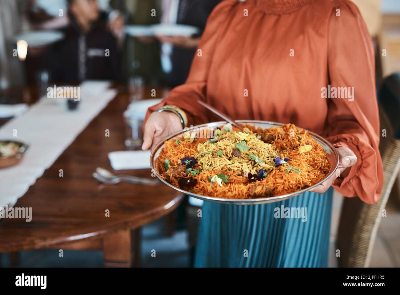 Essen, Abendessen und Verbrauchsmaterialien mit einem traditionellen Paella-Gericht in den Händen einer Frau zu Hause. Nahaufnahme einer Schüssel mit spanischer Meeresnahrung, fertig zum Servieren und Stockfoto