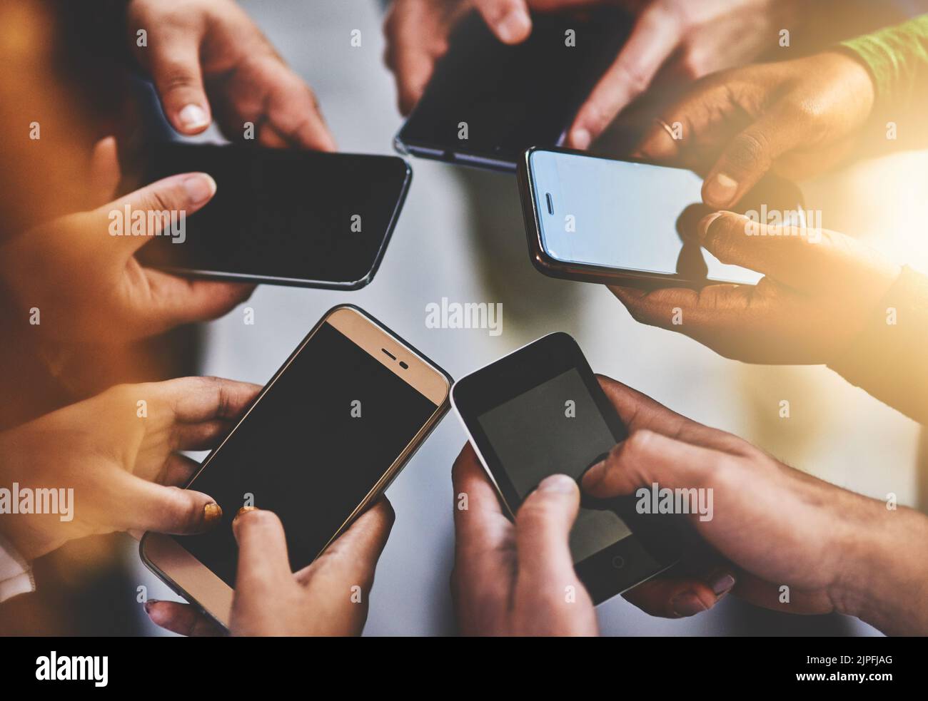 Immer eingeschaltet, immer verbunden. Eine Gruppe von Menschen, die ihr Telefon zusammen benutzen. Stockfoto