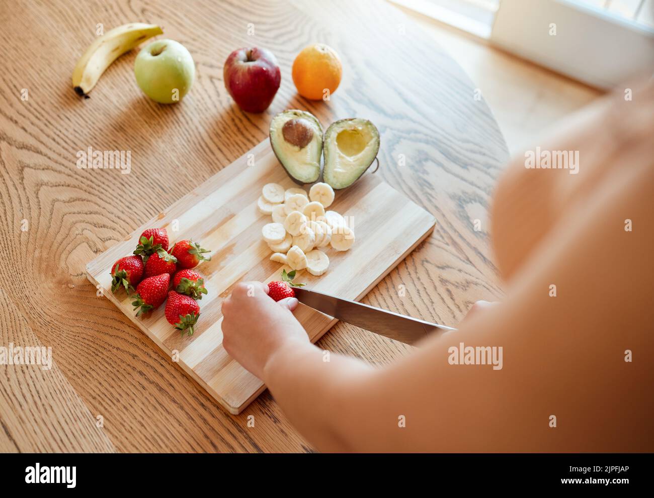 Gesundheit, Ernährung und gesunde Frau schneiden Obst, um einen Smoothie mit Ernährung für eine Bio-Mahlzeit zu Hause zu machen. Nahaufnahme der kaukasischen weiblichen Hände, die hacken Stockfoto