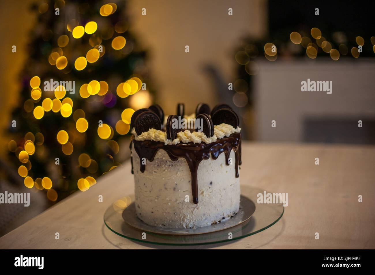 Kuchen mit schwarzen Plätzchen und mit unscharfem christbaumhintergrund Stockfoto