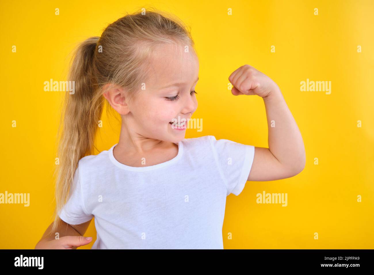 Portrait starke Vorschule kleines Mädchen zeigt Flexing Arm Muskel Lächeln isoliert Stockfoto