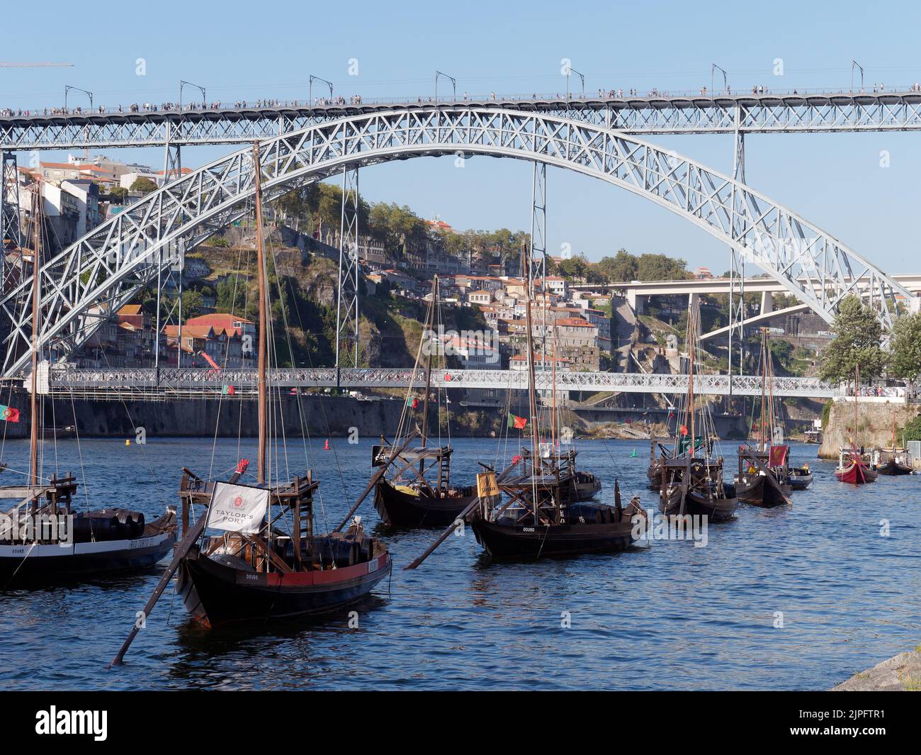 Traditionelle Boote mit Wein auf dem Fluss Douro mit der Luis I-Brücke dahinter, Porto, Portugal. Stockfoto